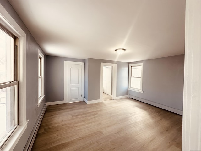 empty room with light wood-style floors, baseboards, and baseboard heating