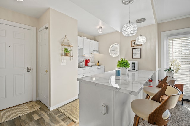 kitchen featuring white appliances, tasteful backsplash, dark hardwood / wood-style flooring, pendant lighting, and white cabinets