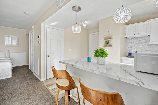 kitchen with light carpet, hanging light fixtures, crown molding, a notable chandelier, and white cabinetry