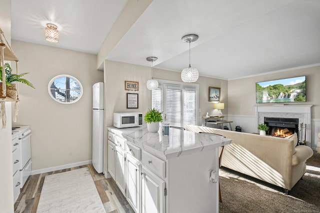 kitchen featuring white appliances, kitchen peninsula, white cabinetry, and plenty of natural light