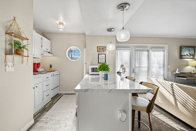 kitchen featuring white appliances, a center island, hanging light fixtures, white cabinets, and hardwood / wood-style flooring