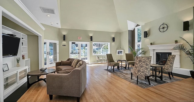 living room with light hardwood / wood-style flooring, french doors, high vaulted ceiling, and crown molding