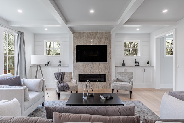 living room featuring coffered ceiling, a fireplace, beamed ceiling, and light wood-type flooring