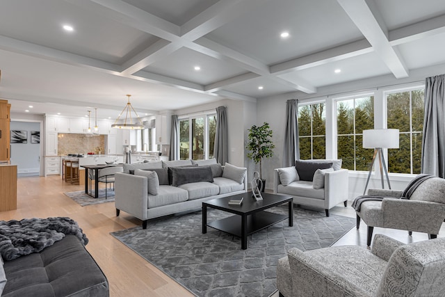 living room featuring coffered ceiling, a notable chandelier, light hardwood / wood-style floors, and beamed ceiling