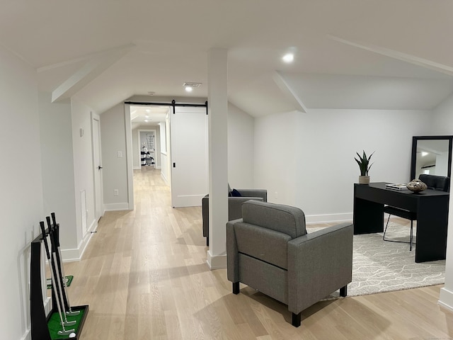 living room with lofted ceiling, a barn door, and light wood-type flooring