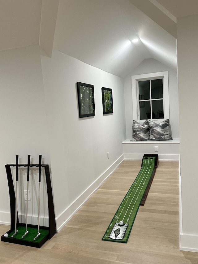 corridor with vaulted ceiling and hardwood / wood-style floors