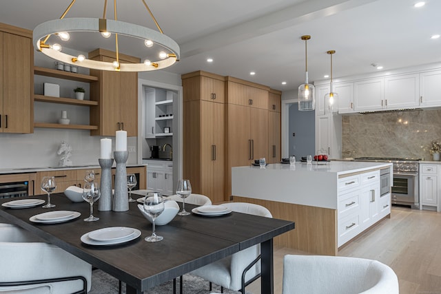 kitchen featuring white cabinetry, light wood-type flooring, tasteful backsplash, and pendant lighting