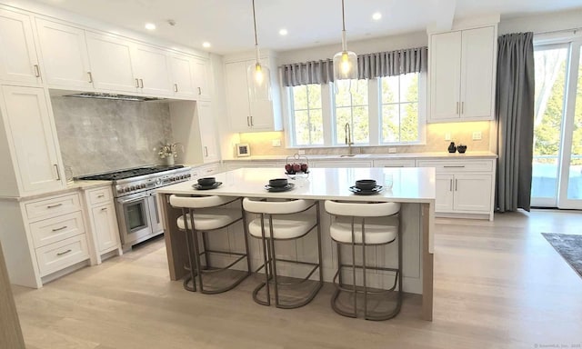 kitchen with white cabinetry, tasteful backsplash, a kitchen bar, and range with two ovens