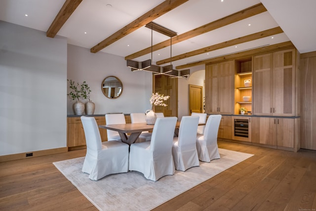 dining area featuring beamed ceiling, beverage cooler, and light hardwood / wood-style flooring