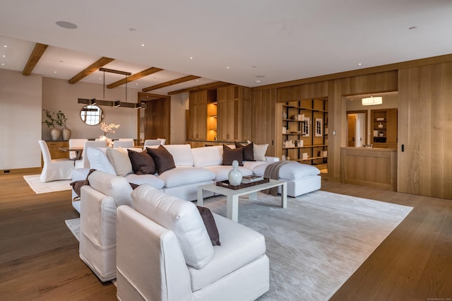 living room with hardwood / wood-style flooring, wooden walls, and beamed ceiling