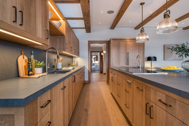 kitchen featuring sink, decorative light fixtures, light hardwood / wood-style flooring, beamed ceiling, and black electric stovetop