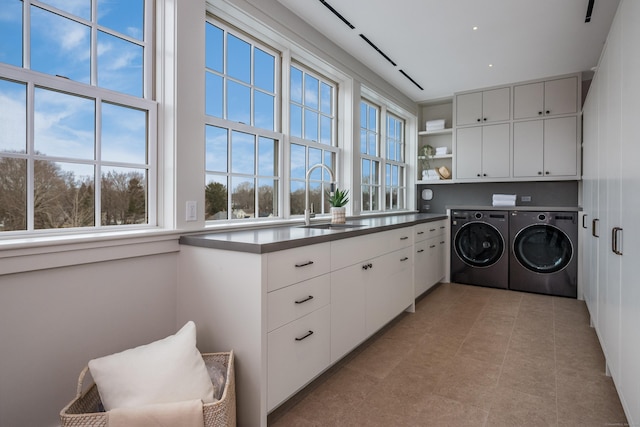 clothes washing area featuring cabinets, sink, and washing machine and clothes dryer