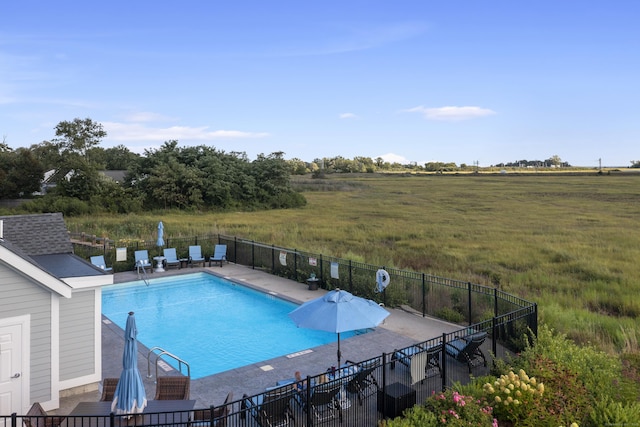 view of pool with a patio, a rural view, and a lawn