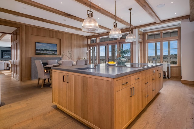 kitchen with a spacious island, sink, light wood-type flooring, pendant lighting, and black electric stovetop