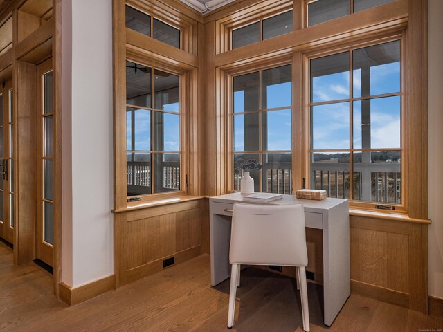 home office with light hardwood / wood-style floors and wood walls