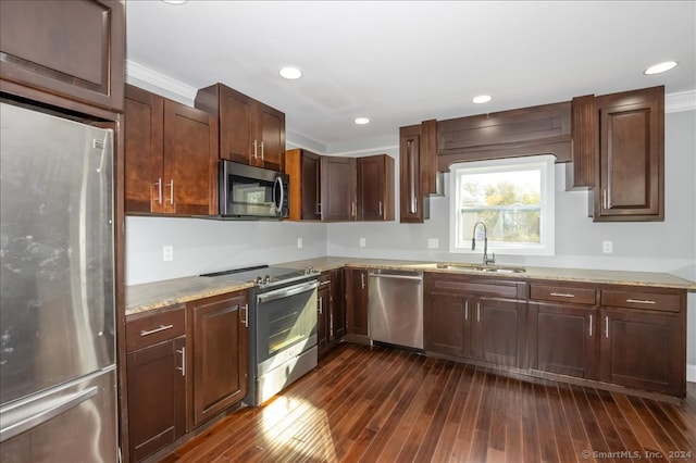 kitchen with dark hardwood / wood-style floors, stainless steel appliances, ornamental molding, sink, and light stone counters