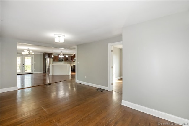 unfurnished living room featuring dark wood-type flooring and a chandelier