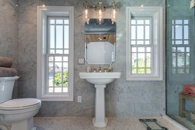 bathroom featuring tile patterned floors, a healthy amount of sunlight, toilet, and tile walls