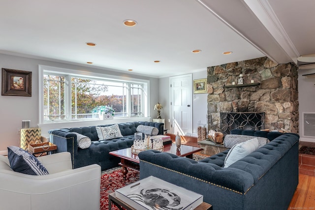 living room featuring a stone fireplace, wood-type flooring, and ornamental molding