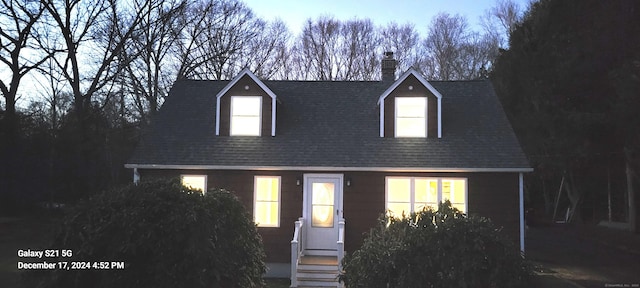 cape cod house with roof with shingles and a chimney