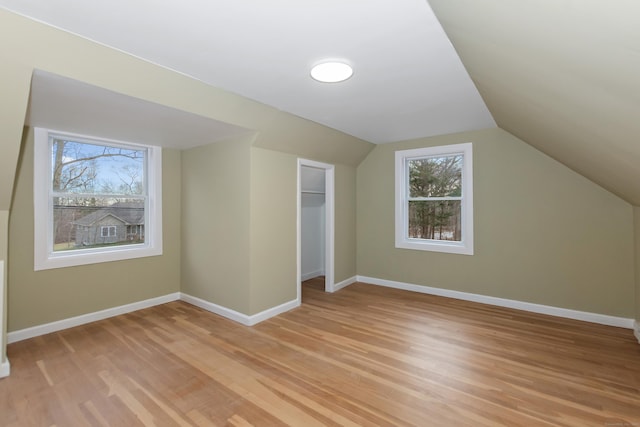 additional living space featuring lofted ceiling, baseboards, and light wood-type flooring