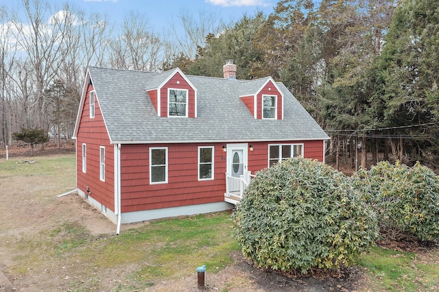 view of front of property with a chimney, a shingled roof, and a front lawn