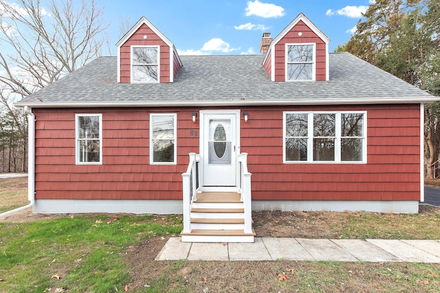 cape cod-style house with a chimney and roof with shingles