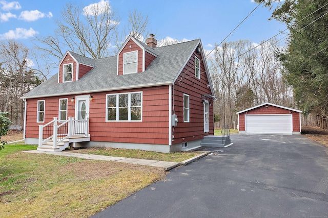 new england style home with roof with shingles, a chimney, an outdoor structure, a front lawn, and a detached garage