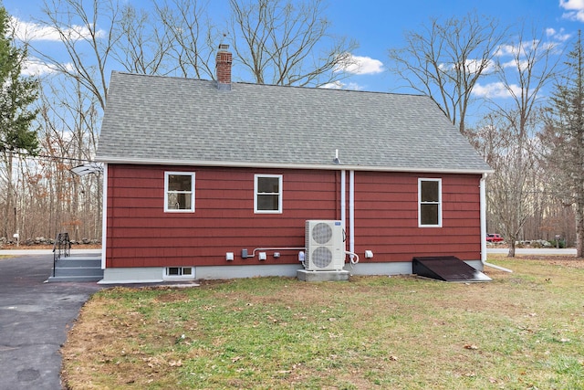 back of property with a lawn, a chimney, and a shingled roof