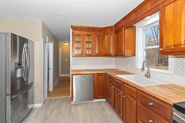 kitchen featuring decorative backsplash, wooden counters, appliances with stainless steel finishes, and a sink