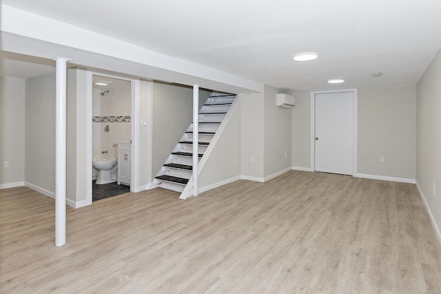 finished basement with baseboards, light wood-style floors, and stairs