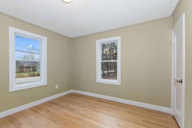 spare room with baseboards and light wood finished floors