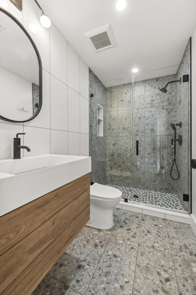 bathroom with tile walls, toilet, vanity, and an enclosed shower