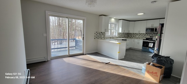 kitchen featuring appliances with stainless steel finishes, white cabinetry, dark hardwood / wood-style floors, a baseboard radiator, and tasteful backsplash