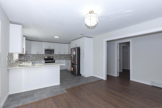 kitchen with a peninsula, white cabinetry, light countertops, appliances with stainless steel finishes, and backsplash