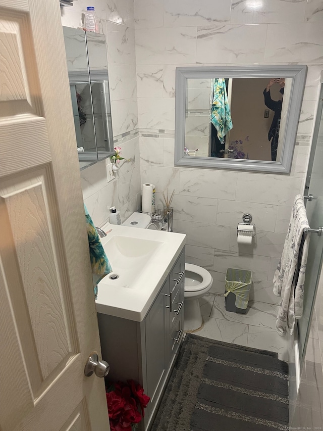 bathroom with tile walls, vanity, and toilet