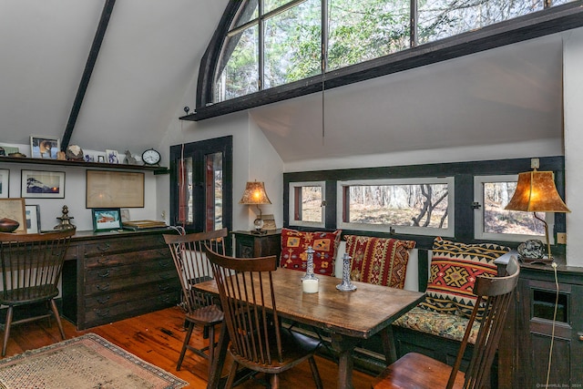 dining area featuring high vaulted ceiling, hardwood / wood-style flooring, and beam ceiling