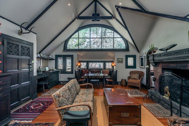 living room featuring high vaulted ceiling, hardwood / wood-style flooring, a brick fireplace, and beam ceiling