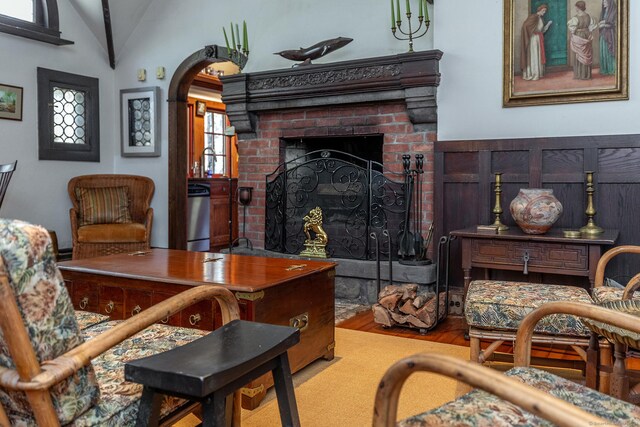 51 Wykeham Rd, Washington, CT 06793 - living area featuring vaulted ceiling, wood finished floors, arched walkways, and a brick fireplace