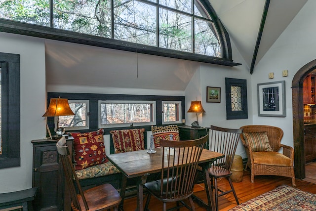 dining space with hardwood / wood-style floors and high vaulted ceiling