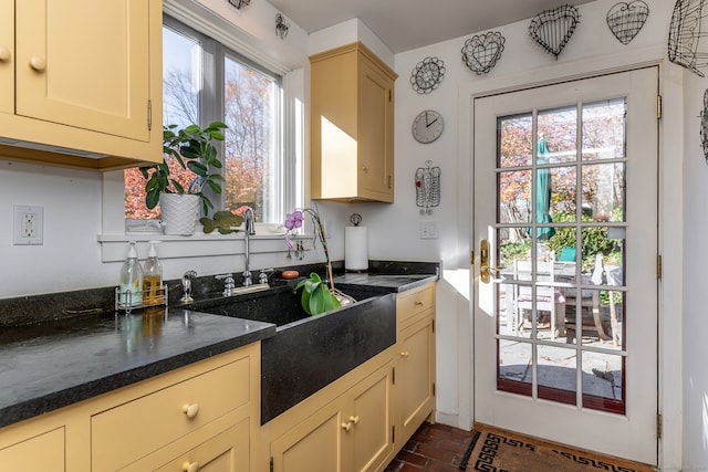 kitchen featuring a healthy amount of sunlight, sink, and dark stone counters