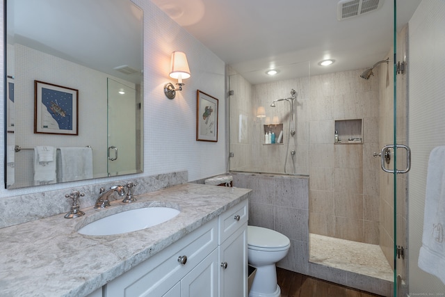 bathroom with vanity, hardwood / wood-style flooring, tile walls, toilet, and a shower with shower door