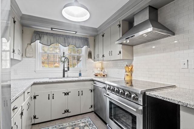 kitchen with high end stove, backsplash, sink, and wall chimney exhaust hood