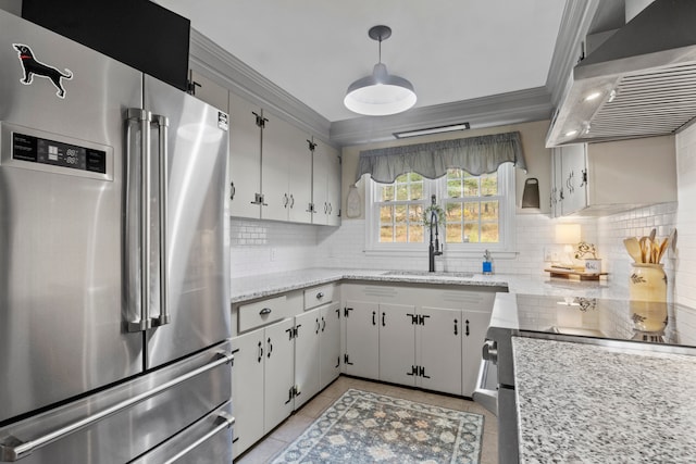 kitchen featuring white cabinets, wall chimney exhaust hood, sink, high end refrigerator, and pendant lighting