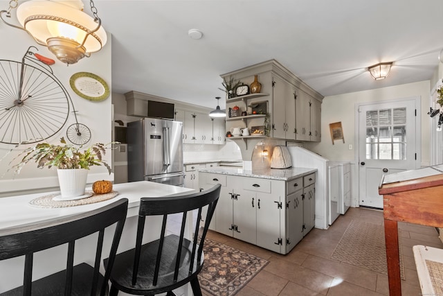 kitchen featuring high end refrigerator, light tile patterned floors, decorative light fixtures, and kitchen peninsula