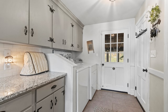 laundry area featuring washer and clothes dryer, cabinets, and light tile patterned flooring