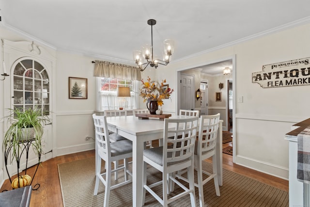 dining area featuring dark hardwood / wood-style flooring, a notable chandelier, and crown molding