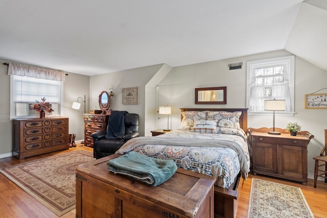 bedroom featuring multiple windows, light hardwood / wood-style flooring, and vaulted ceiling