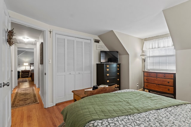 bedroom with hardwood / wood-style flooring, a closet, and lofted ceiling