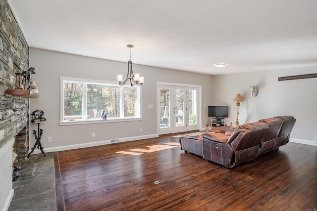 living room with a fireplace, dark hardwood / wood-style flooring, and an inviting chandelier